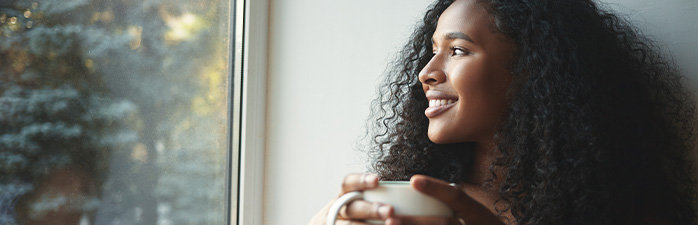 African-american woman drinking tea and looking out window